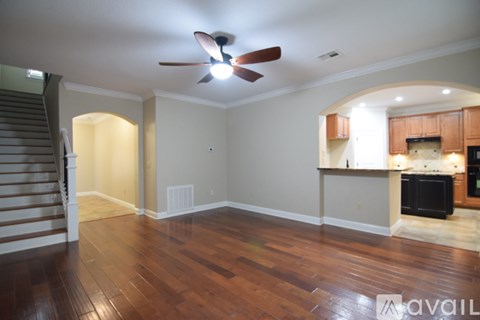 A living room with a ceiling fan and hardwood floors.