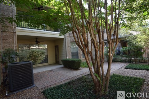 A tree in a yard with a house in the background.