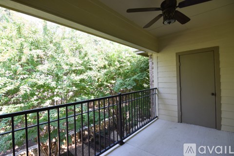 A balcony with a fan and trees in the background.