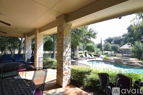 A patio with a table and chairs overlooks a pool.