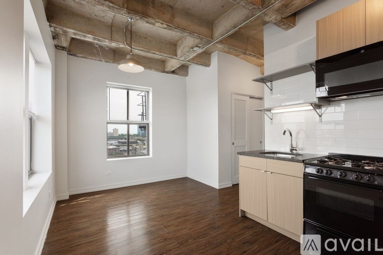 A kitchen with a black stove top oven and wooden floors.