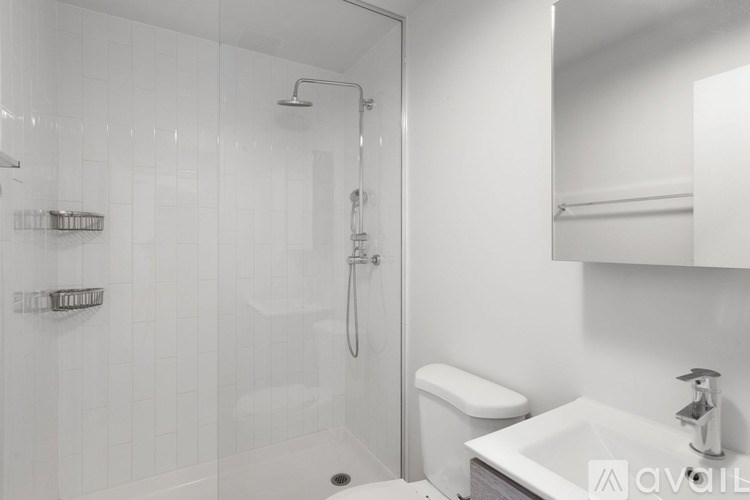 A white bathroom with a walk in shower and a toilet.