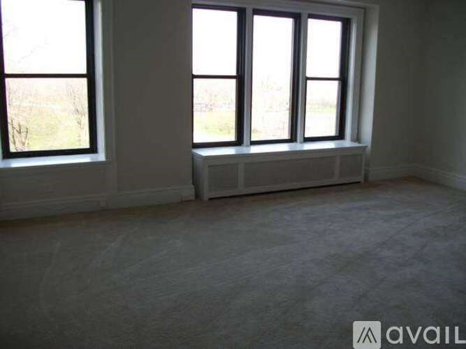 A room with three windows and a carpeted floor.