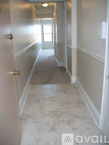 A hallway with marble flooring and white walls.
