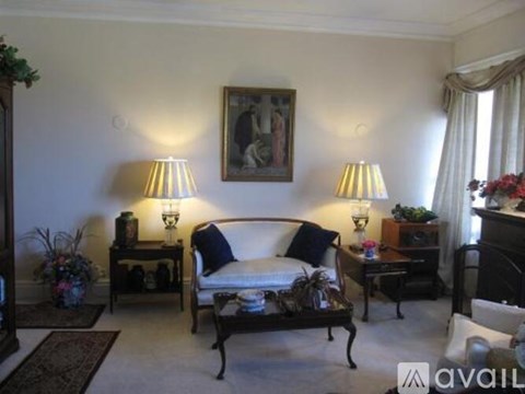 A living room with a couch, two lamps, and a painting on the wall.