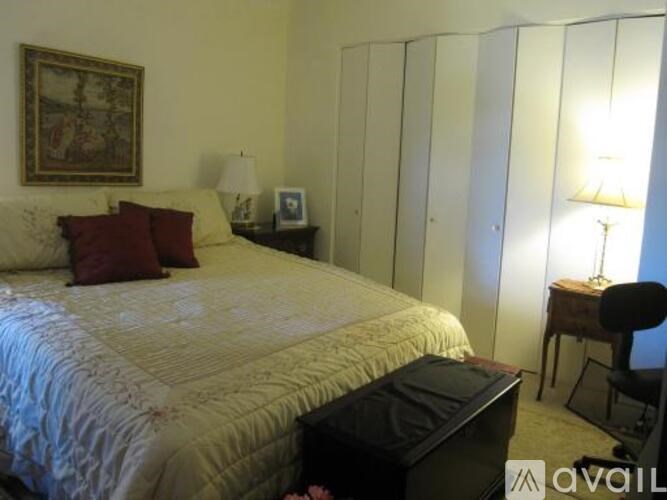 A bedroom with a bed, a chair, and a painting on the wall.