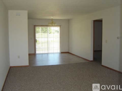 A room with a carpeted floor and a chandelier hanging from the ceiling.