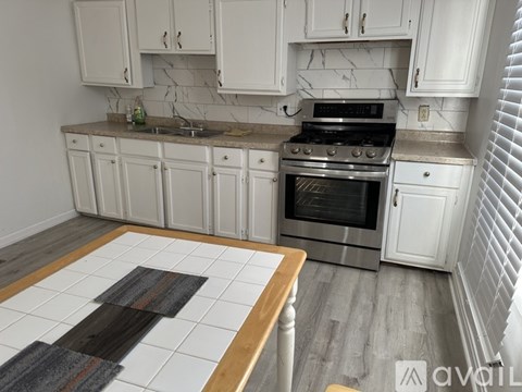 A kitchen with white cabinets and a marble backsplash.