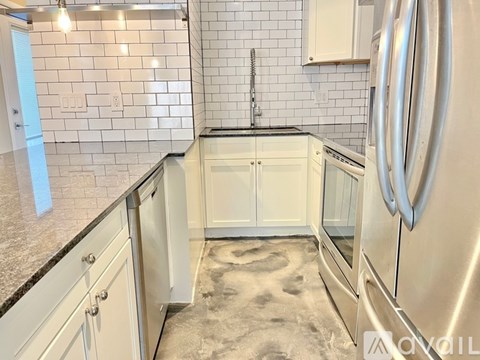 A kitchen with white cabinets and a stainless steel refrigerator.