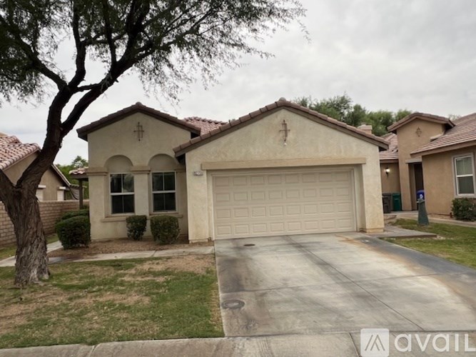 A house with a garage and a tree in front.
