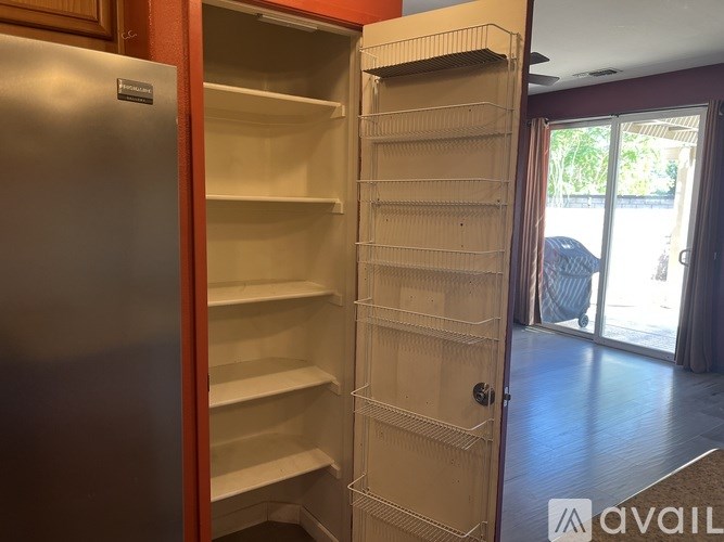 A kitchen with a refrigerator and an empty pantry.