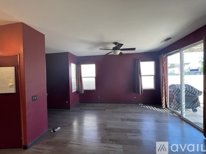 A room with a ceiling fan and sliding glass doors.