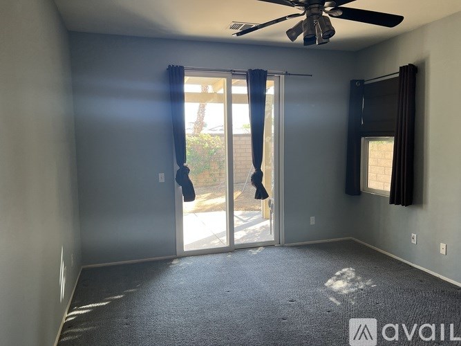 A room with a ceiling fan and sliding glass doors leading to a patio.