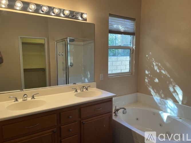 A bathroom with a large mirror, double sinks, and a bathtub.