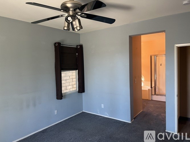 A room with a ceiling fan and a window with blinds.