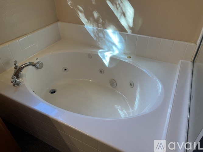 A white bathtub with a silver faucet and a sunlight reflection on the wall.