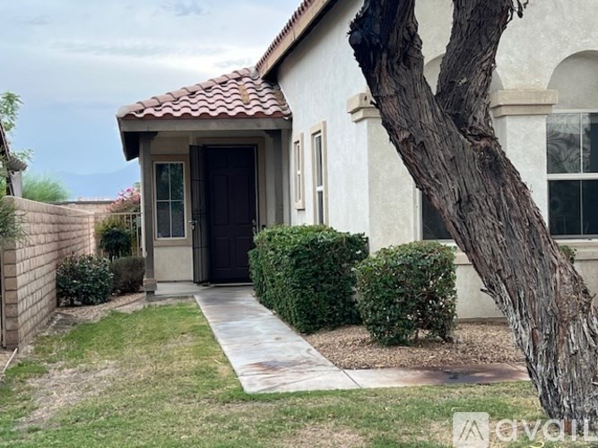 A house with a brown door and a tree in front.