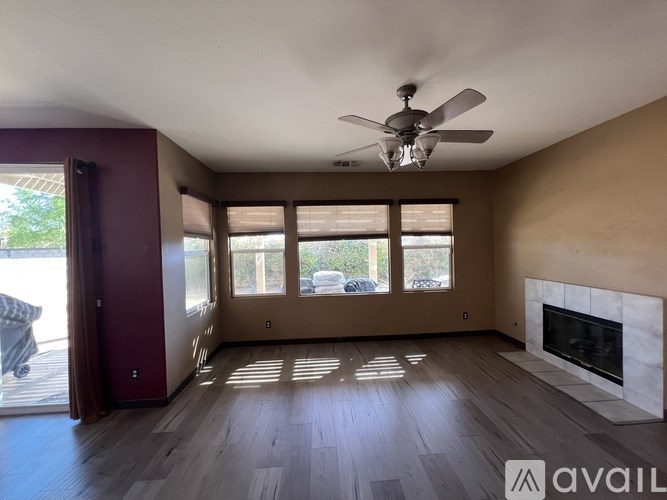 A spacious living room with a fireplace and a ceiling fan.