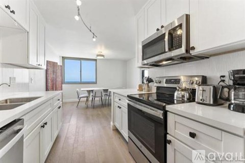 A kitchen with white cabinets and a wooden floor.