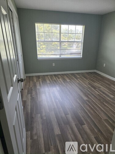 A room with wooden flooring and a window.
