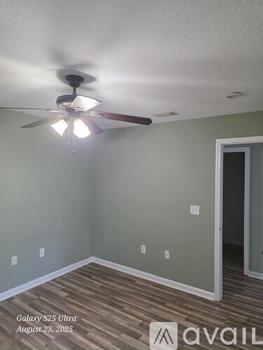 A room with a ceiling fan and wooden flooring.
