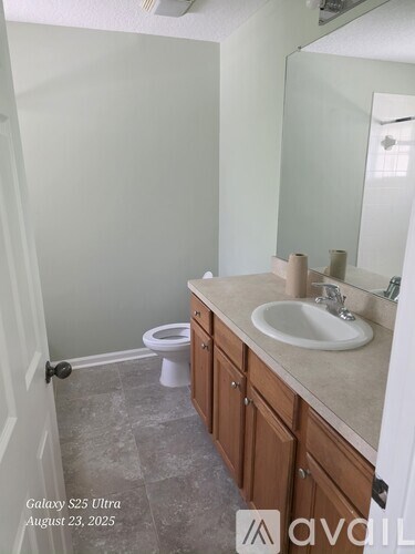 A bathroom with a toilet, sink, and cabinets.