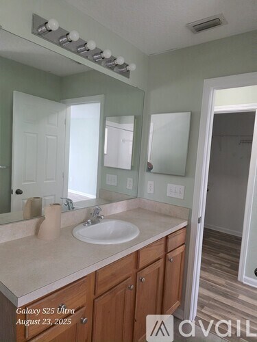A bathroom with a sink, mirror, and lighting fixture.