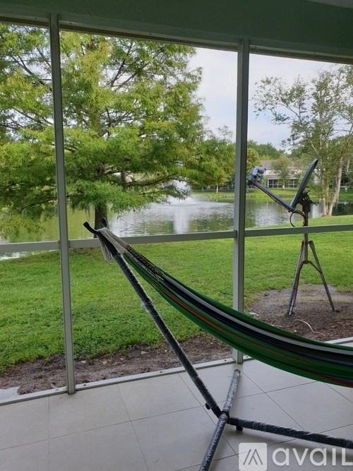 A hammock is strung between two windows overlooking a pond.