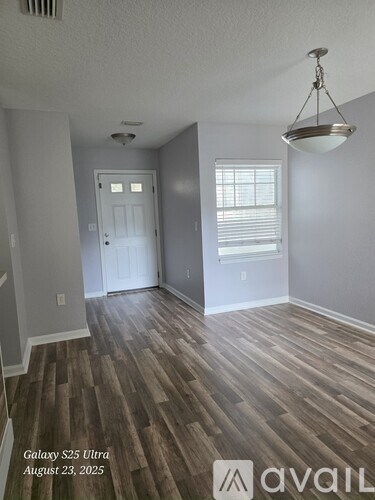 A room with wooden flooring and a hanging light fixture.