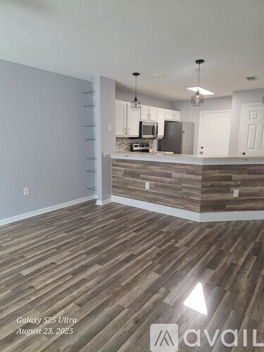 A kitchen with wooden flooring and a white wall.