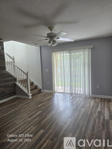A room with a ceiling fan and wooden flooring.