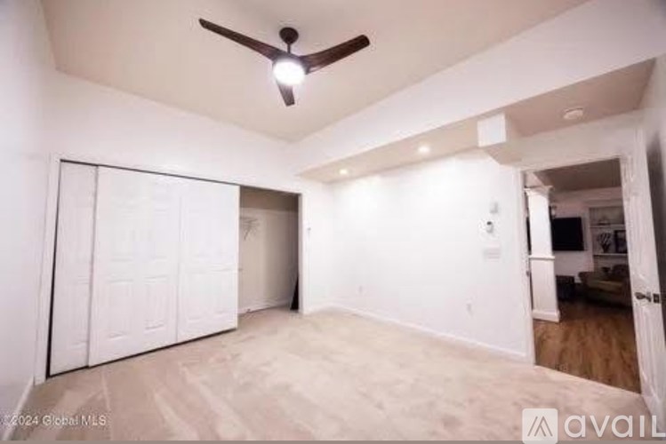 A room with a ceiling fan and a white door.