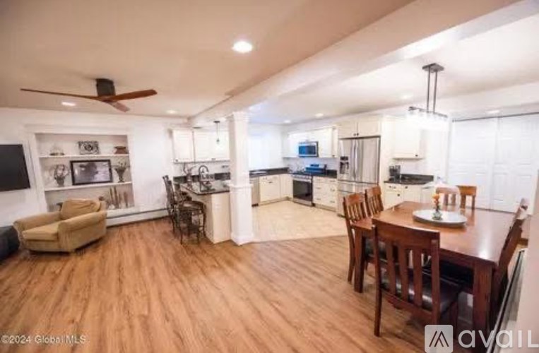 A well-lit open plan living and dining area with a kitchen in the background.