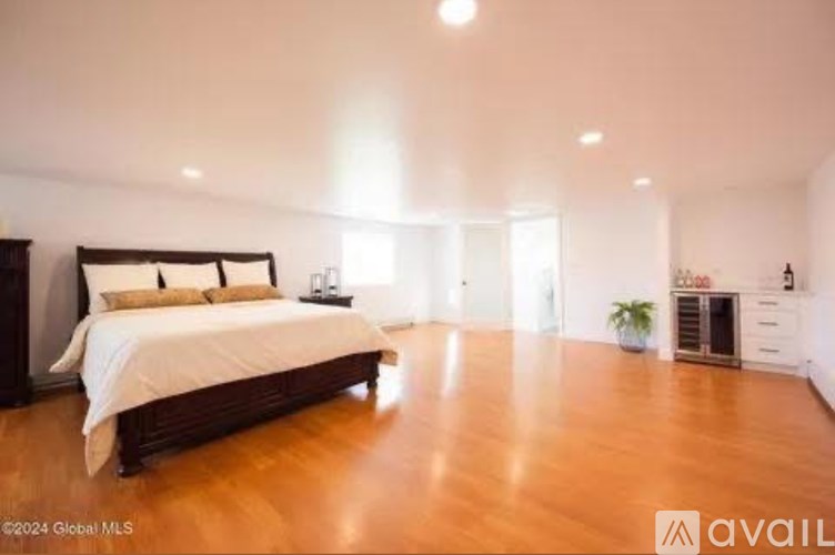 A bedroom with a large bed and wooden floors is available for rent.