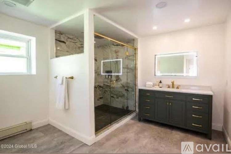 A bathroom with a walk-in shower and a vanity with a mirror.