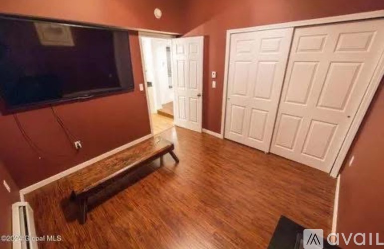 A room with a flat screen TV mounted on the wall and a wooden floor.