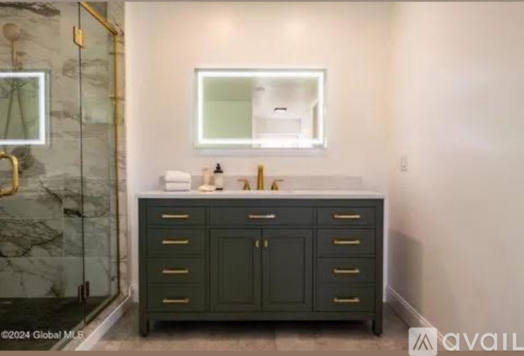 A bathroom with a marble shower and a vanity with a mirror above it.
