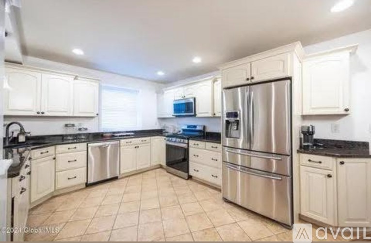A kitchen with white cabinets and a stainless steel refrigerator.