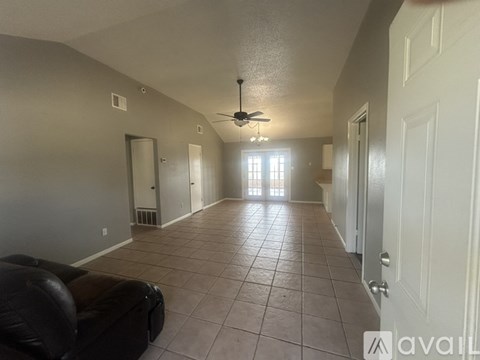 A living room with a black leather couch and a ceiling fan.