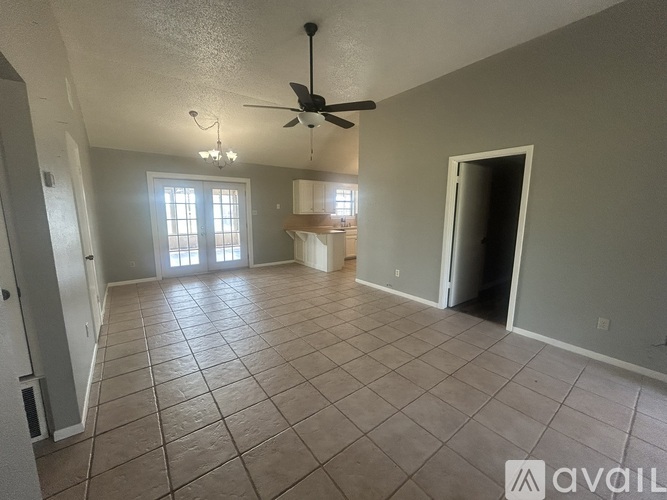 A spacious room with tile flooring and a ceiling fan.
