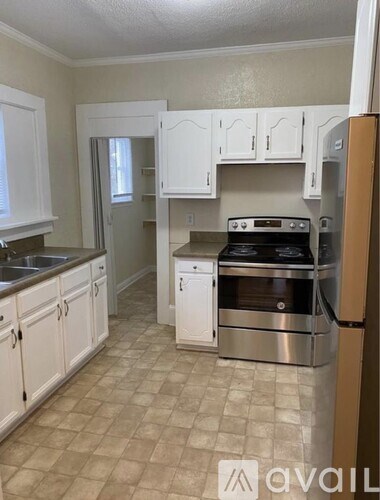 A kitchen with white cabinets and a tile floor.