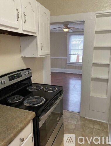 A kitchen with a stove top oven and white cabinets.
