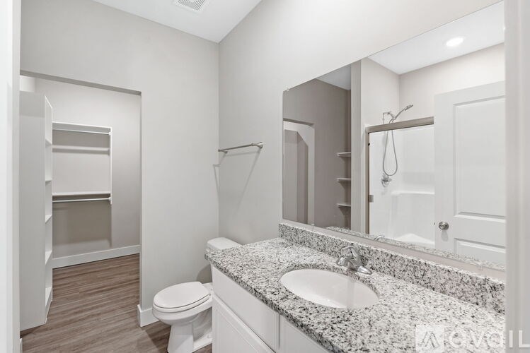 A bathroom with a toilet, sink, and mirror.