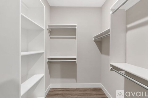 A white walk-in closet with shelves and a wooden floor.