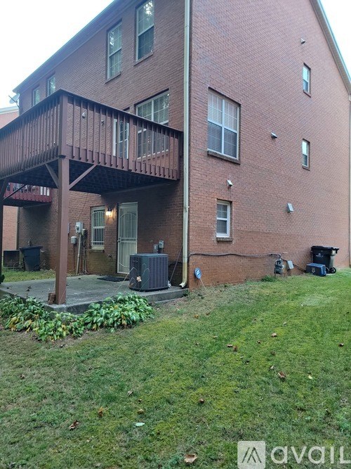 A red brick building with a balcony and a green lawn in front.