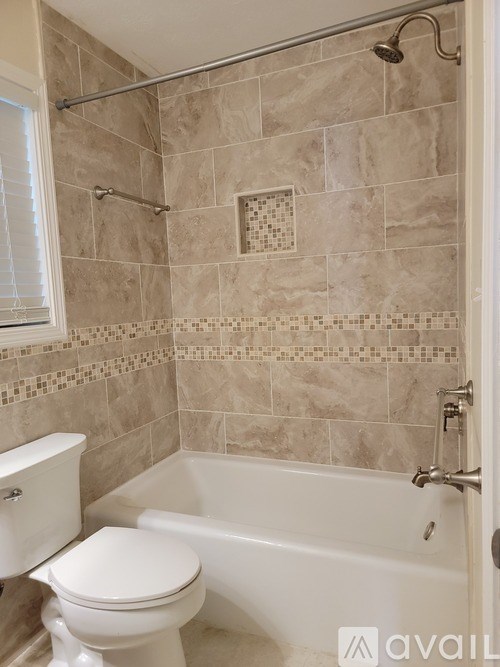 A bathroom with a toilet, tub, and tiled walls.