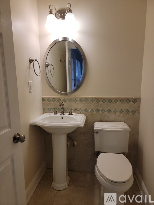 A bathroom with a toilet, sink and mirror.