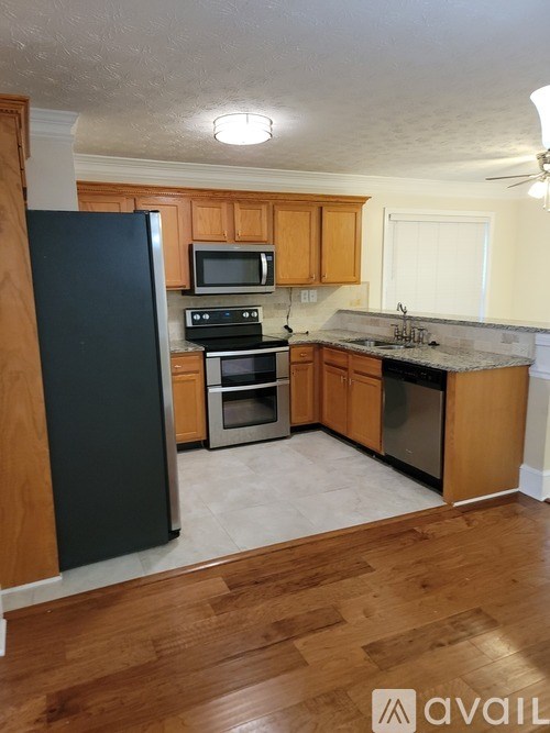 A kitchen with wooden cabinets and a black refrigerator.