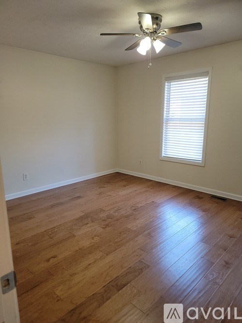 A room with wooden flooring and a ceiling fan.