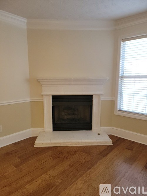 A white fireplace with a black screen in a room with wooden floors.